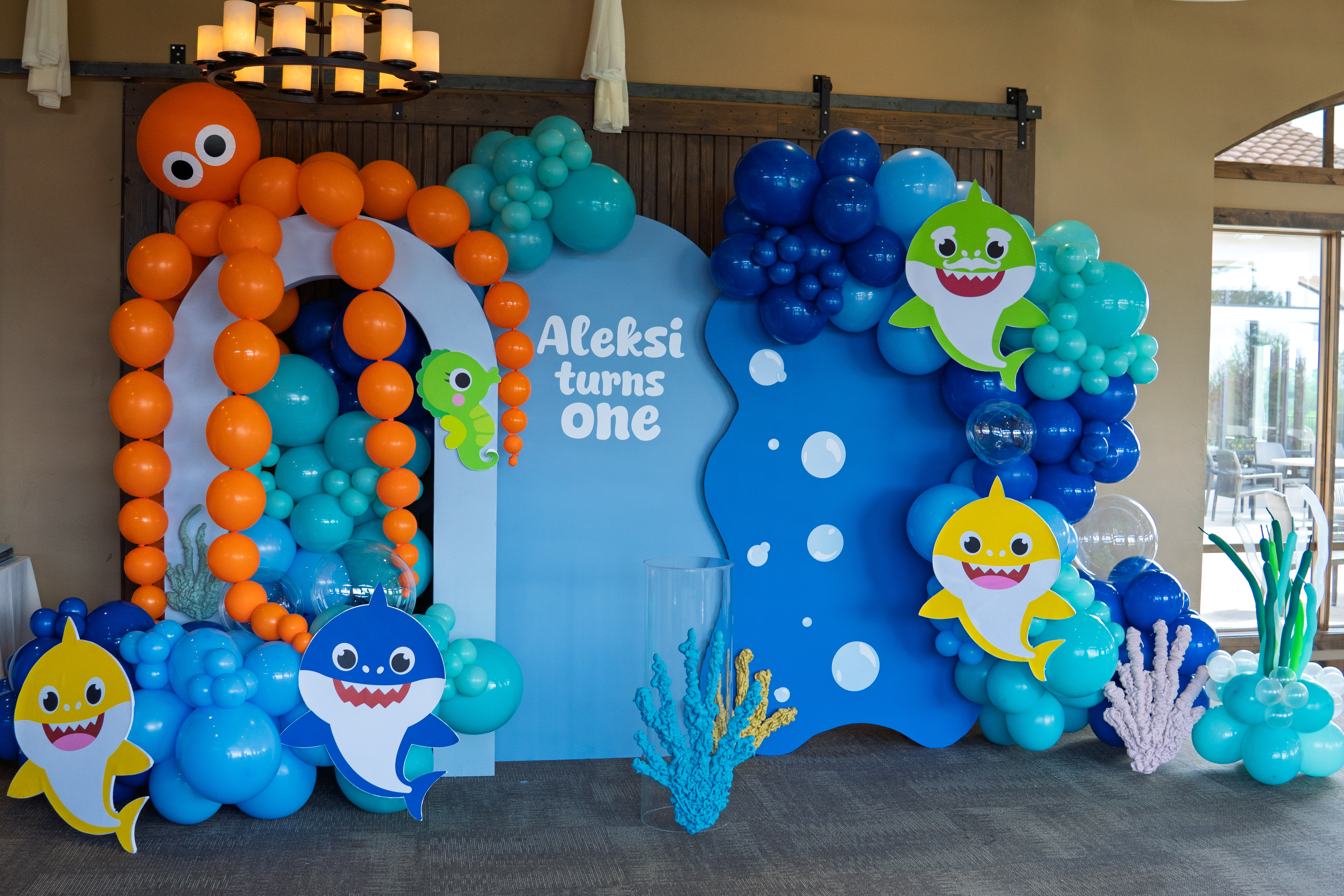 Ocean-themed first birthday party setup by Chuchi's Events, a Denver-based party rental and balloon decor company. Features custom balloon garlands and arches, sea creature props, Baby Shark cutouts, and layered backdrop rentals. Full-service installation includes luxury balloon styling, themed props, and event setup—perfect for kids' parties and milestone celebrations in the Denver metro area