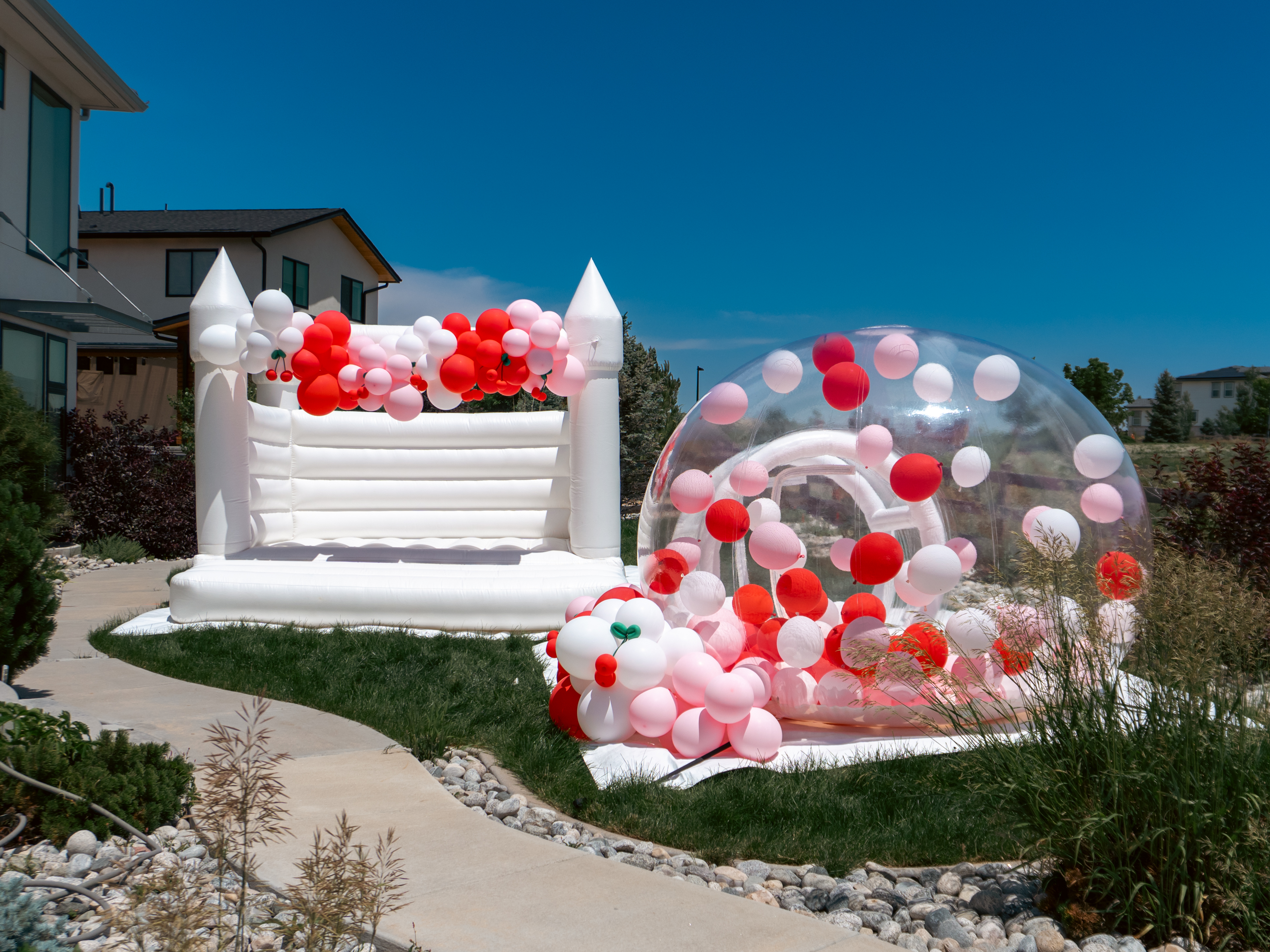 Cherry-themed white bounce house and bubble house rental in Denver by Chuchi’s Events, featuring custom balloon decor for birthdays, weddings, and stylish kids’ parties.
