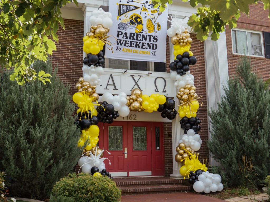 Balloon arch and column installation in black, gold, white, and yellow for Alpha Chi Omega Parents Weekend event in Boulder, Colorado. Custom sorority balloon decor by professional balloon decorators for college events, parties, and Greek life celebrations.