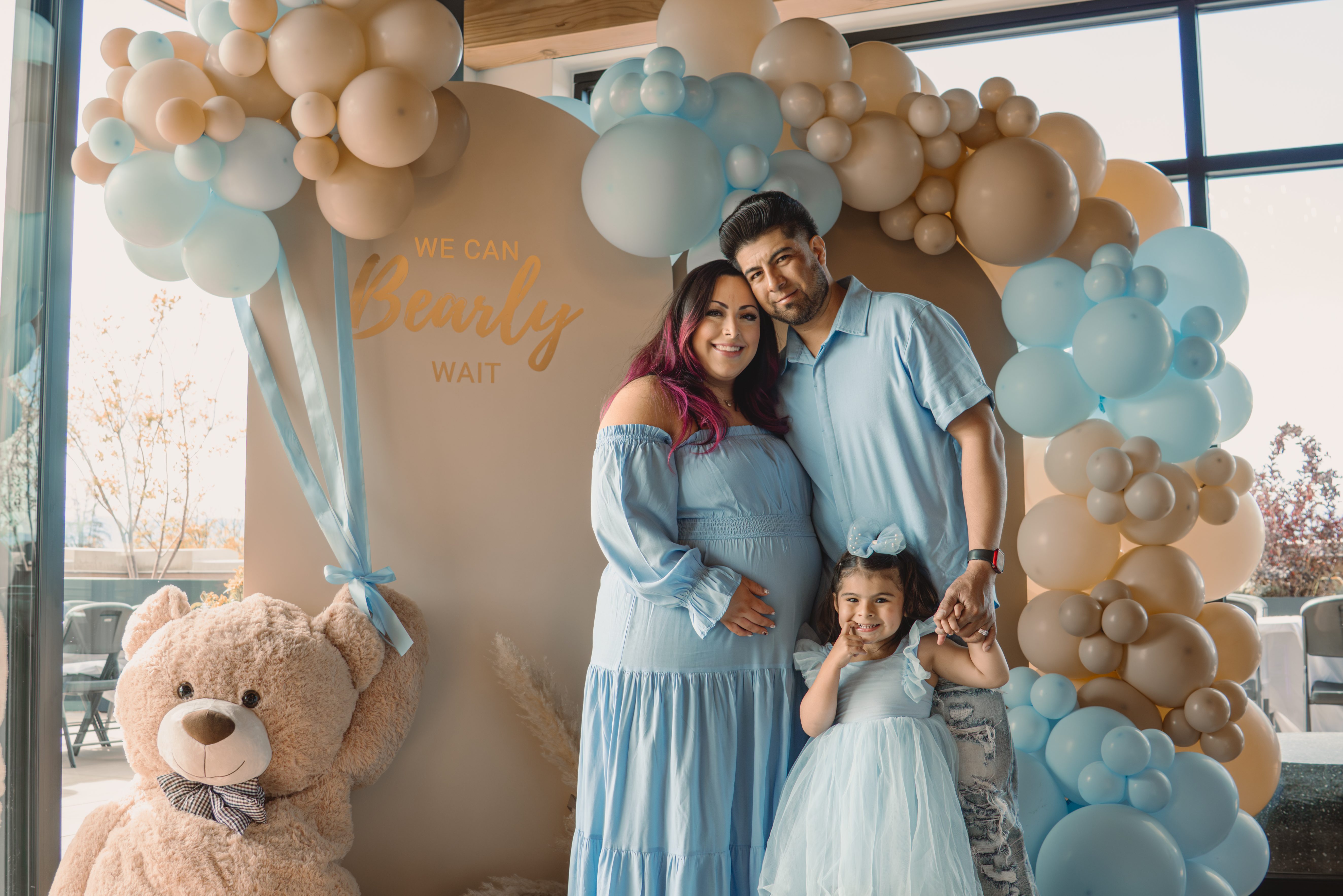 Balloon garland setup for a Denver We Can Bearly Wait themed baby shower, featuring a giant teddy bear, blue and neutral balloons and custom backdrops. 