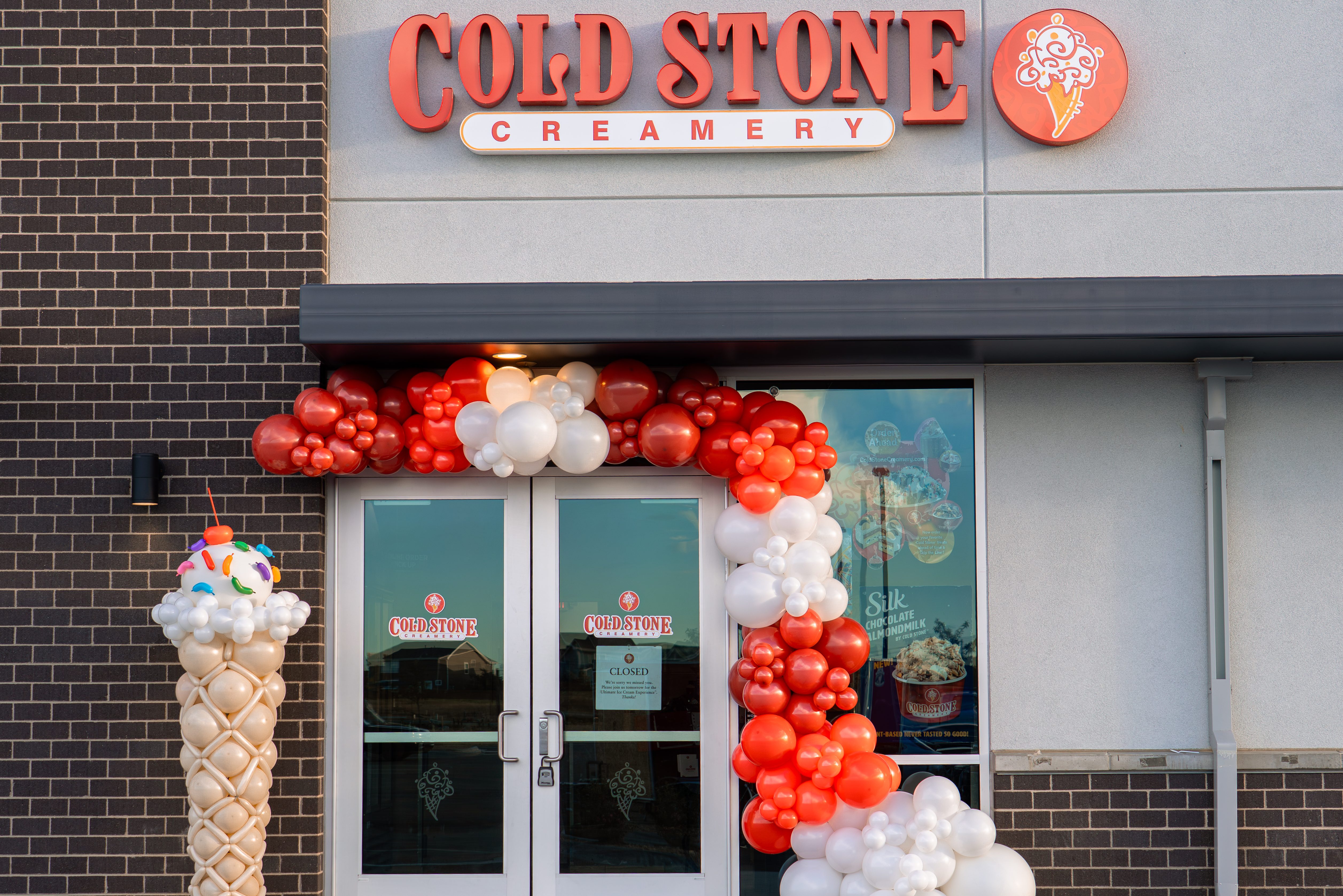 Custom corporate balloon installation for a Denver Cold Stone Creamery grand opening, including branded colors, ice cream cone balloon column, and event decorations.